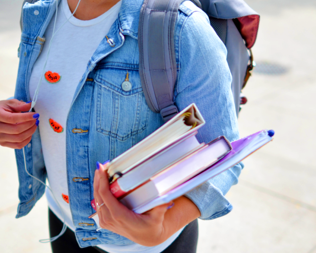 Woman wearing blue denim jacket holding books