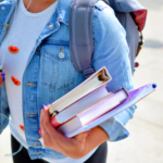 Woman wearing blue denim jacket holding books