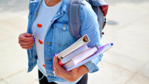 Woman wearing blue denim jacket holding books