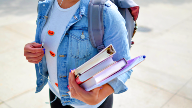 Woman wearing blue denim jacket holding books
