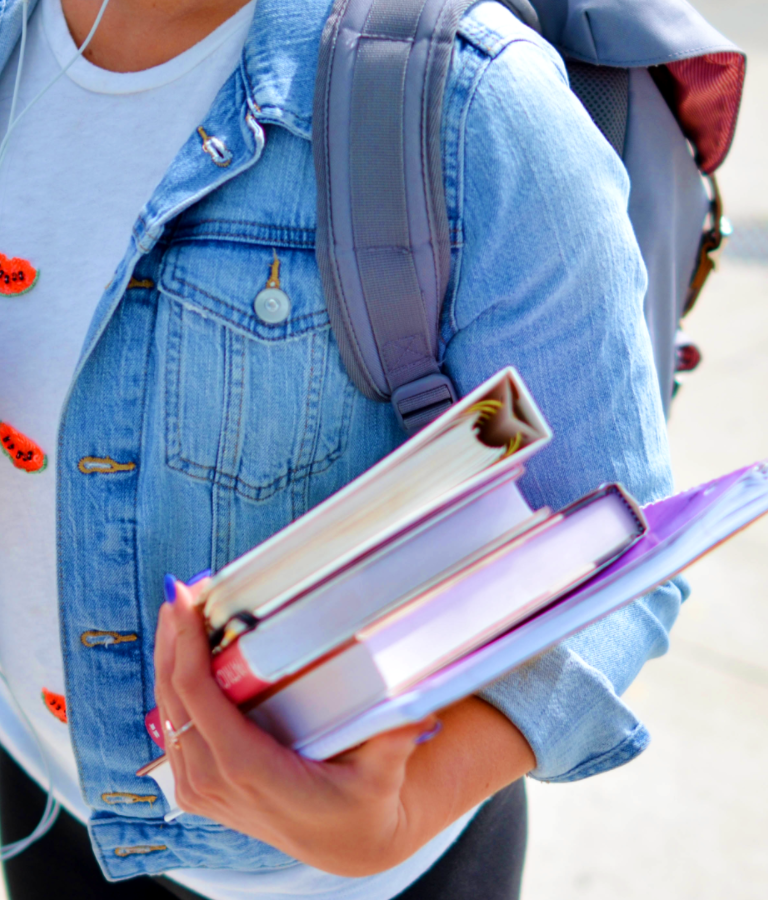 Woman wearing blue denim jacket holding books