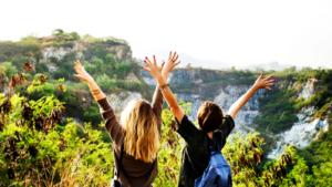 Two women in front of a mountain throwing their hands in the air