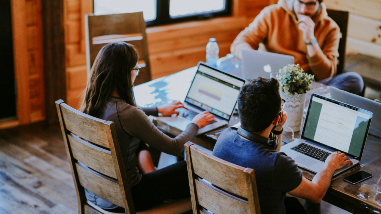 Selective focus photography of woman and man using MacBook Pro on table