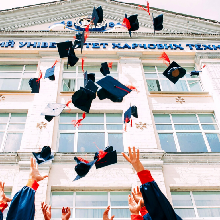 group of fresh graduates students throwing their academic hat in the air