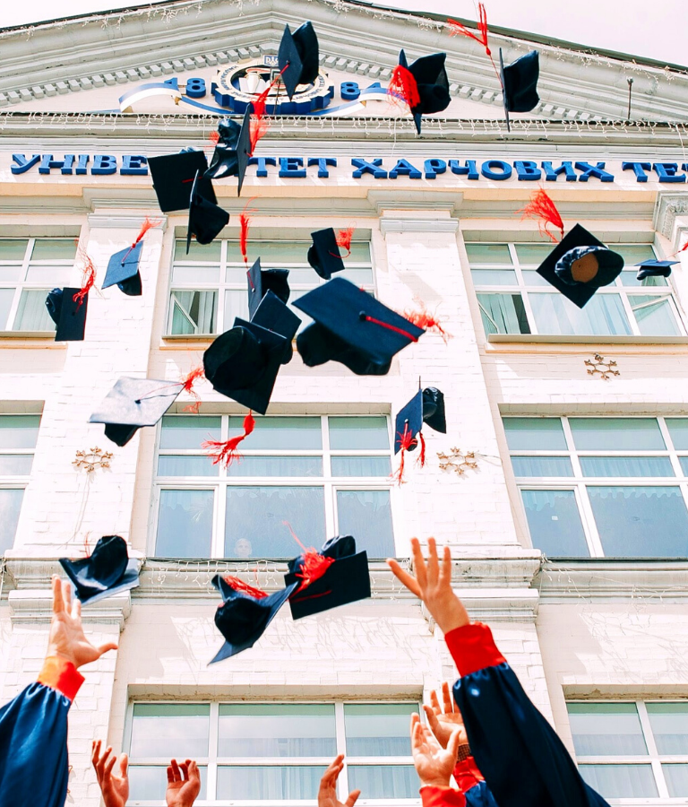 group of fresh graduates students throwing their academic hat in the air