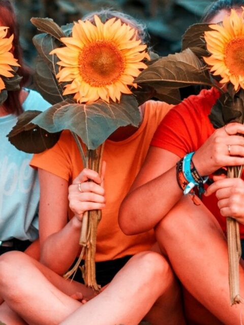 Three women holding sunflowers