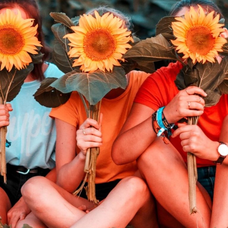 Three women holding sunflowers