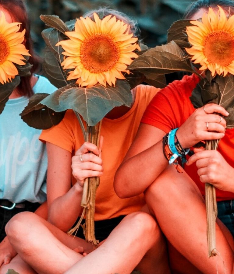 Three women holding sunflowers