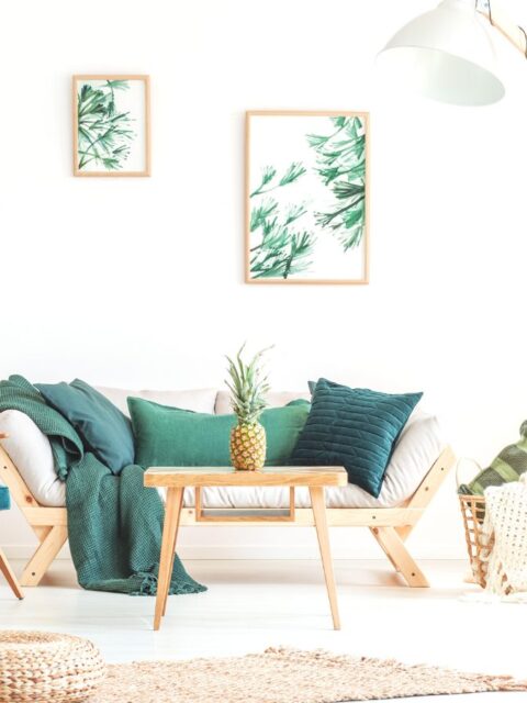 Pineapple on wood stool in living room with green furniture and braided pouf on carpet