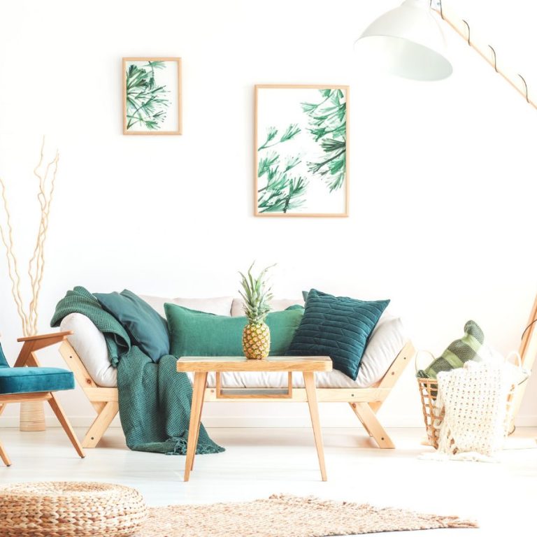 Pineapple on wood stool in living room with green furniture and braided pouf on carpet