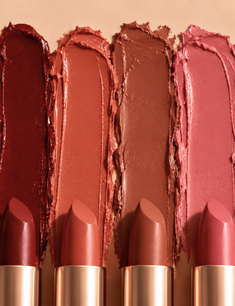 Six fall-inspired lipstick shades in deep berry, burgundy, terracotta, warm brown, dusty rose, and brick red, shown as lipstick swatches with matching lipstick bullets